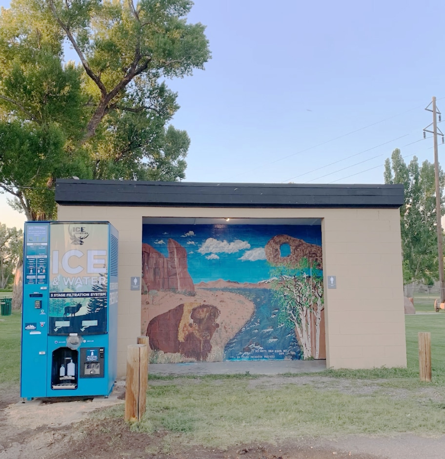 A custom branded Ice Hunters Ice and Water vending machine outside of a public bathroom