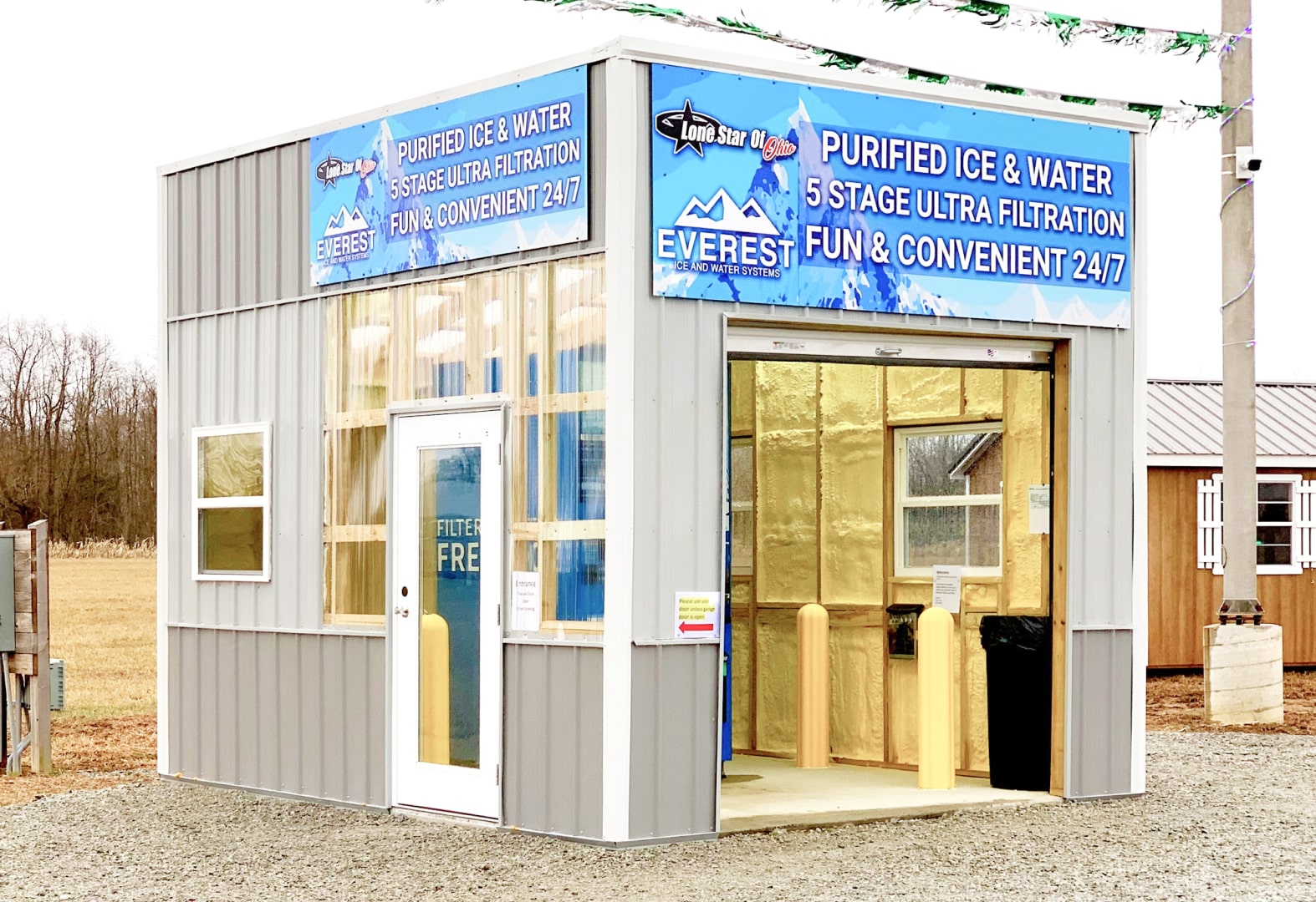 A portable storage building with Lone Star of Ohio branding on it where an Everest Ice and Water vending machine is housed