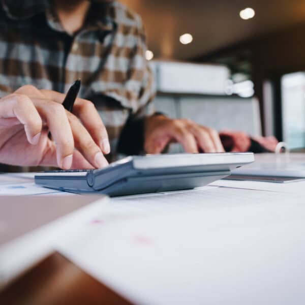 Business,Man,Holding,Pen,And,Using,Smartphone,For,Calculating,Financial